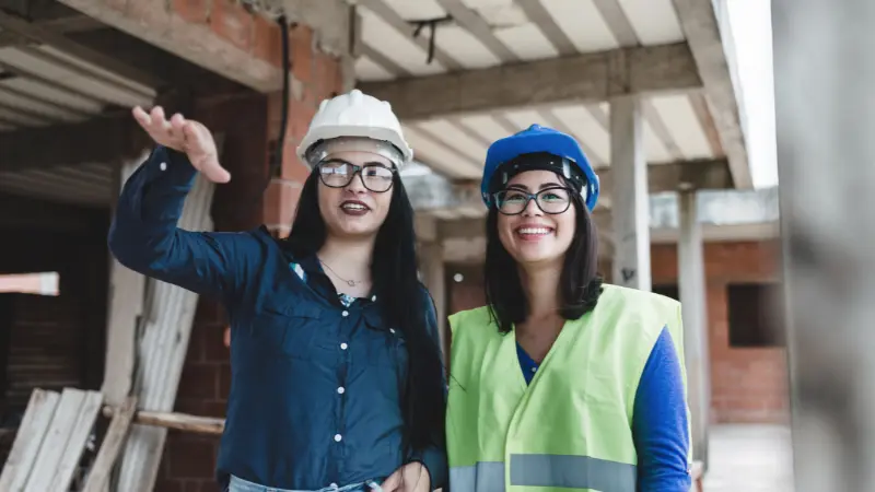 Women construction workers reviewing work on a job site during Women in Construction Week.